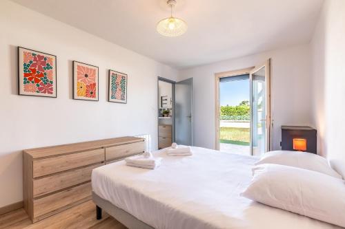 a white bedroom with a large bed and a window at Gemma - 5 min de la Plage in Ondres