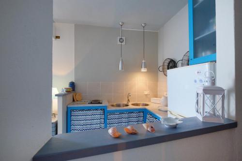uma cozinha com um balcão azul e uma geladeira branca em La finestra sul mare em Cagliari