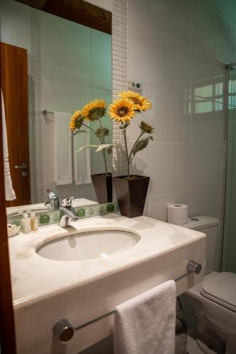 a bathroom with a sink with a vase of yellow flowers at Pousada Bela Aurora in Venda Nova do Imigrante