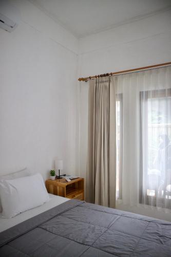 a white bedroom with a bed and a window at Isirela in Kuta Lombok