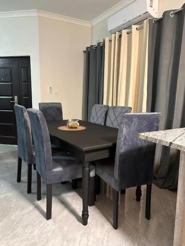 a dining room table with blue chairs and a black table at Modern and cozy apartment in Lusaka