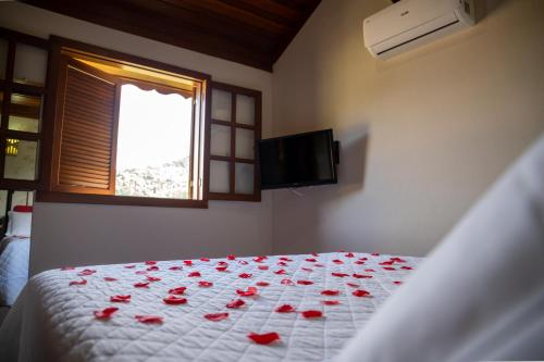 a bedroom with a bed with red roses on it at Pousada Bela Aurora in Venda Nova do Imigrante