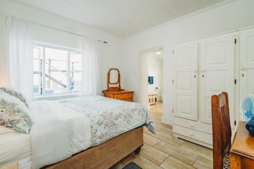 a bedroom with a bed and a dresser and a window at Silver Spray Beach Accommodation in Victoria Bay