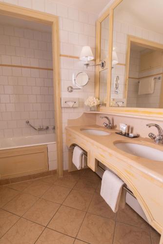 a bathroom with a sink and a tub and a mirror at Le Grand Hôtel - Domaine De Divonne in Divonne-les-Bains
