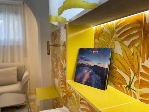 a room with a yellow wall with a picture on it at Tender to Carafa in Capri