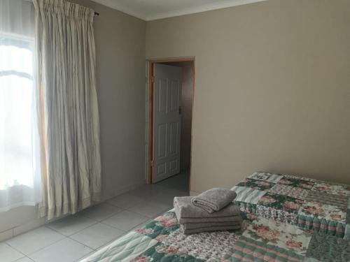 a bedroom with a bed with a quilt and a window at Home Sweet Home in Polokwane