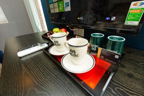 two coffee cups on a table with a remote control at Belvilla Near Tan Son Nhat International Airport - Formerly Havana Hotel in Ho Chi Minh City