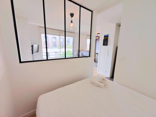 a bedroom with a white bed with a mirror at Saint Ruth - Apartment for 2 with private parking in Lille