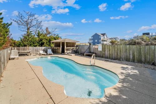 a swimming pool in a backyard with a fence at By the See in Waves