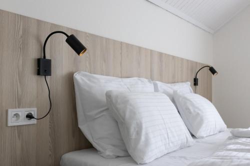 a bed with white pillows and a wooden headboard at Hotel Sport Houštka 