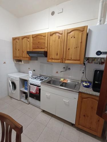 a kitchen with a sink and a stove and wooden cabinets at Valentin Monfalcone Apartment near Fincantieri and Marina Julia in Monfalcone