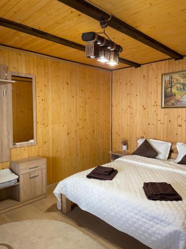 a bedroom with a bed and a wooden wall at Dimira Котедж з басейном in Slavske