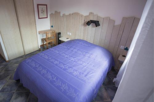 a bedroom with a blue bed and a wooden wall at Gites au Cœur de la Nature, Piscine et Vue sur le Lac du Salagou in Le Puech