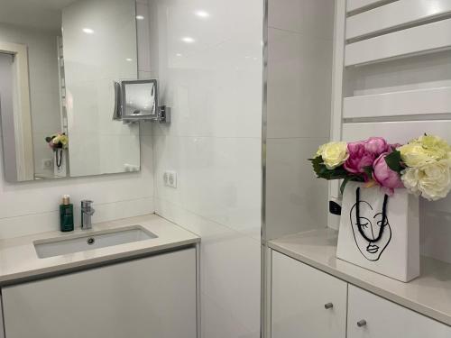 a bathroom with a sink and a vase of flowers at Hotel Le Fouquet's in Cannes