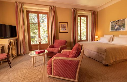 a bedroom with a bed and two chairs and a television at Le Grand Hôtel - Domaine De Divonne in Divonne-les-Bains