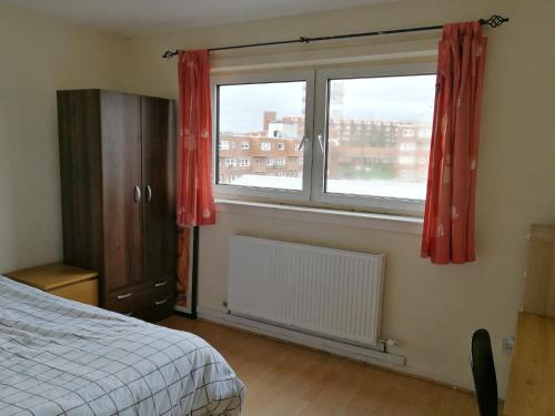 Un dormitorio con una cama y una ventana con cortinas rojas. en Glasgow Room near Glasgow City Centre, en Glasgow