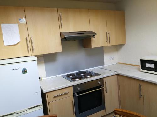 Una cocina con gabinetes de madera y un horno de estufa. en Glasgow Room near Glasgow City Centre, en Glasgow