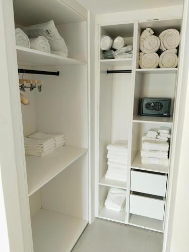 a white closet with white shelves and towels at Prado Suites Las Terrenas in Las Terrenas