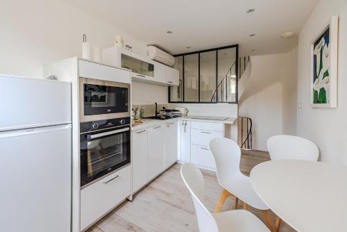 - une cuisine blanche avec des appareils électroménagers et des chaises blanches dans l'établissement Maison Liberation - Centre Tourrettes sur Loup, à Tourrettes-sur-Loup