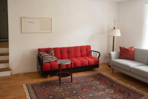 a living room with a red couch and a table at dasFritsch-Historisches Weinbauernhaus im Grünen in Klein-Reinprechtsdorf