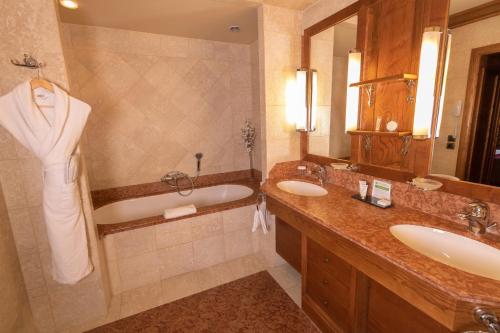 a bathroom with a tub and two sinks and a bath tub at Le Grand Hôtel - Domaine De Divonne in Divonne-les-Bains