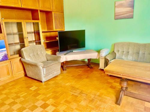 a living room with two chairs and a flat screen tv at Ride & Rest, Budget, Waschmaschine, Wohnzimmer, Küche, Radlgarage in Altötting