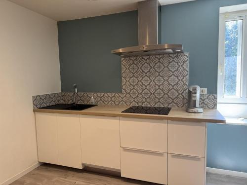 a kitchen with white cabinets and a stove top oven at Charmant appartement Gramat in Gramat