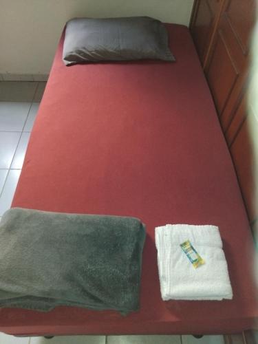 a bed with red sheets and a towel on it at Hospedagem Sousa Santos in Montes Claros