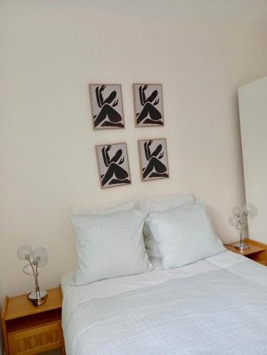 a bedroom with a white bed with four pictures on the wall at Modern apartment! in Hazebrouck