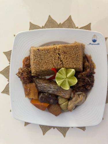 a plate of food with a sandwich and vegetables at Résidence Cheikh Mahy Cisse Appartements, studios et chambres a louer meublé et climatisé in Kaolack