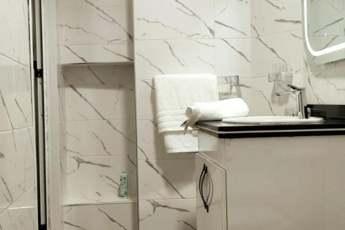 a white bathroom with a shower and a sink at Corniche House in Nador