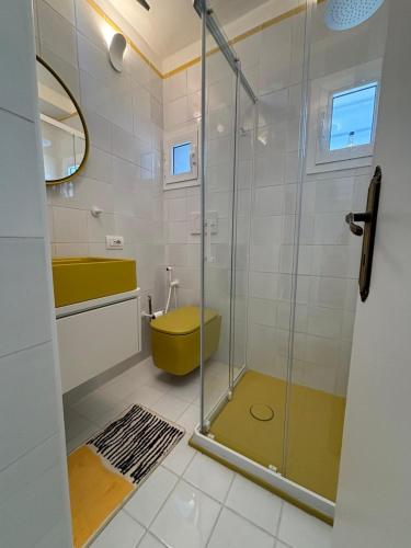 a bathroom with a glass shower and a yellow toilet at Tender to Carafa in Capri
