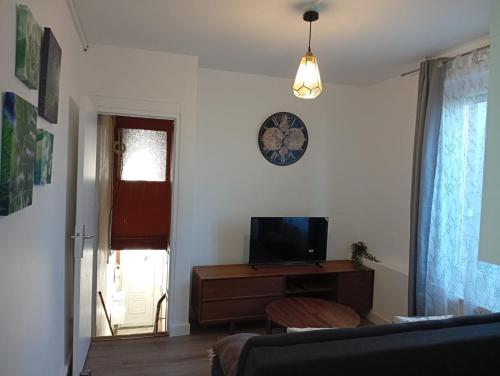 a living room with a television and a clock on the wall at Modern apartment! in Hazebrouck