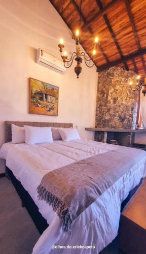 a bedroom with a large bed and a stone wall at Fazenda Capuava in Bananal