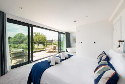 a bedroom with a large bed and a balcony at Huron House ML06 Lower Mill Estate Cotswolds in Somerford Keynes