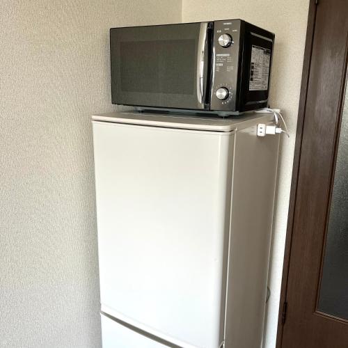 a microwave sitting on top of a refrigerator at Guest House Loyal HAKATA in Fukuoka