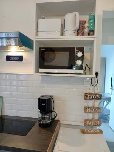 a kitchen with a microwave above a counter at Modern apartment! in Hazebrouck