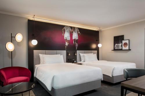 a hotel room with two beds and a chair at Radisson RED London Twickenham in Twickenham