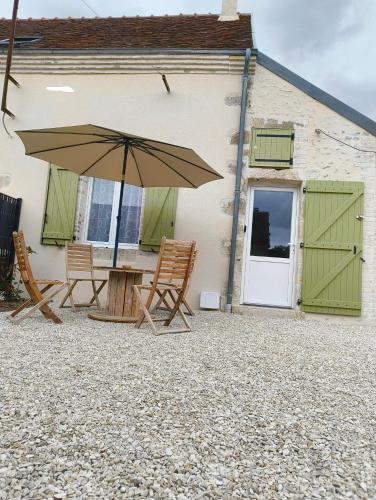 a patio with a table and chairs and an umbrella at Gite l'ancien four à pain calme et douillet in Breteau
