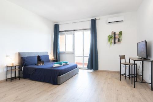 a bedroom with a blue bed and a large window at Leonardo Da Vinci Guest House in Fiumicino