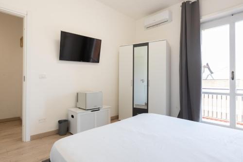 a bedroom with a white bed and a tv on the wall at Leonardo Da Vinci Guest House in Fiumicino