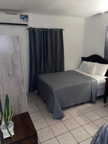 a bedroom with a bed with a gray blanket and curtains at bamboo bed and breakfast in San Pedro Sula