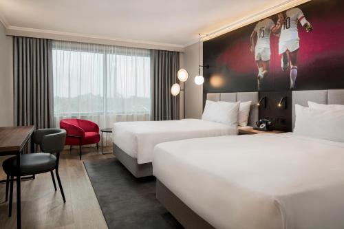 a hotel room with two beds and a desk at Radisson RED London Twickenham in Twickenham