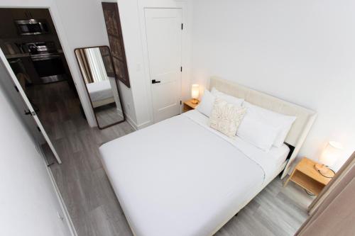 a bedroom with a large white bed and a mirror at Lux Capitol Hill Vacation Home, In-House Services in Washington