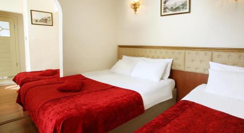 two beds in a hotel room with red blankets at Masal Otel in Kocaeli
