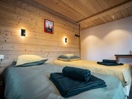 two beds in a room with wooden walls at Chalet 6 pièces neuf, 12 pers, 3 sdb, parking, terrasse, proche remontées - FR-1-676-193 in Châtel