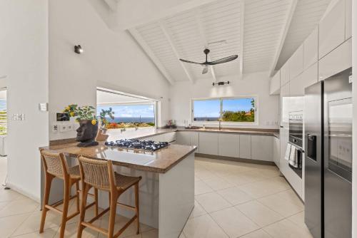 a kitchen with white cabinets and a counter with stools at Dream View Villa in Willemstad