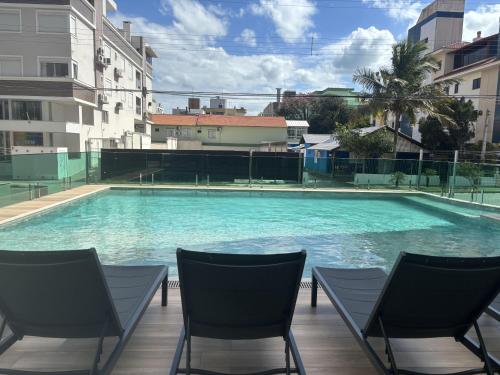 a large swimming pool with chairs and buildings at Varadero Palace Hotel in Florianópolis