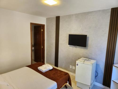 a small room with a bed and a tv on the wall at Deck de Búzios in Búzios