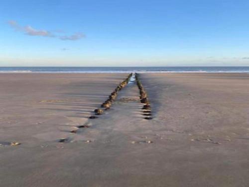 a pier sticking out of the sand on a beach at House in Zingem near Hiking Trails in Zingem